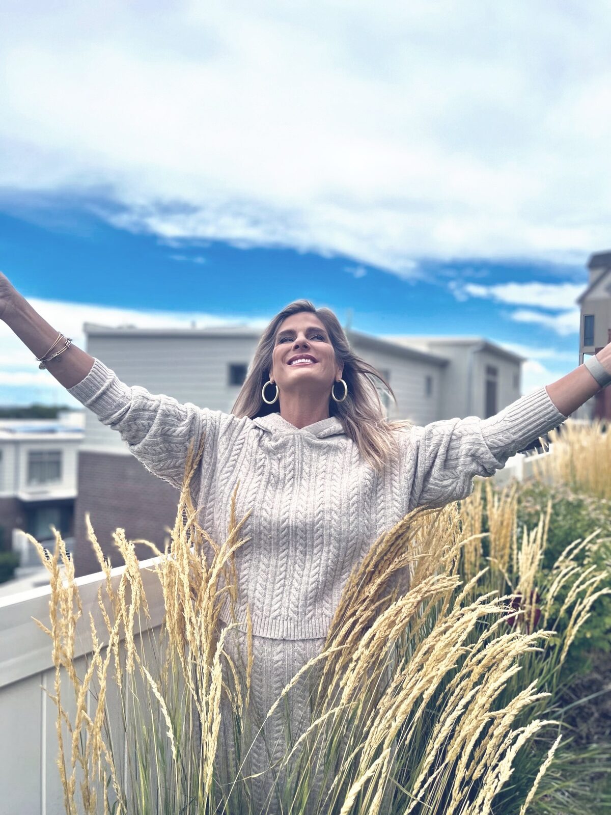 Athena Metos, LMFT, outdoors with her arms raised